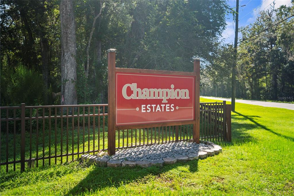 A red sign for Champion Estates stands in a grassy area near a metal fence — REPUBLICAN (LOT 7) WAY, BROOKSVILLE, FL