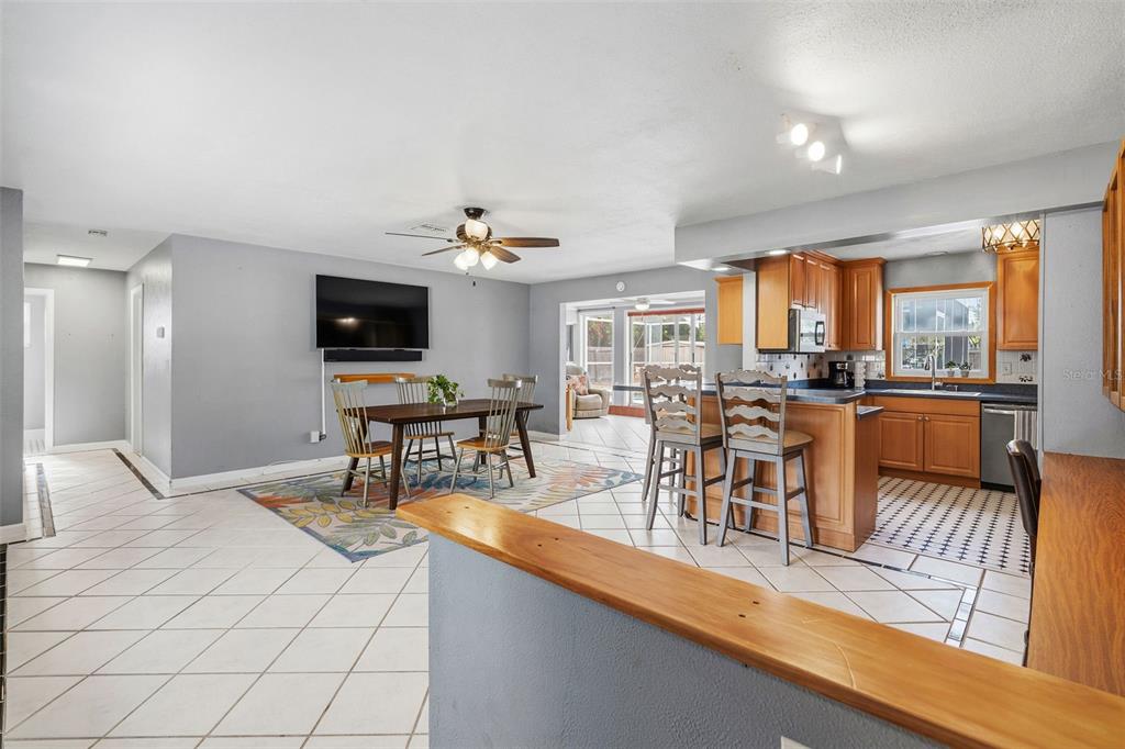 An open-concept living and dining area features tile flooring, wood cabinets, and a breakfast bar — 4333 71ST AVENUE N, PINELLAS PARK, FL