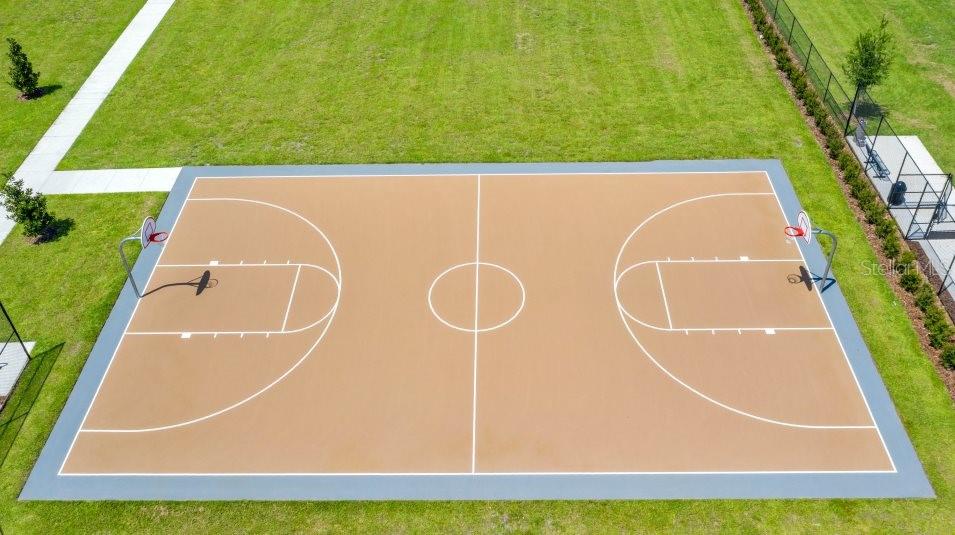 An aerial view shows an outdoor basketball court surrounded by grass and a fence — 3917 AMERS LOOP, HAINES CITY, FL