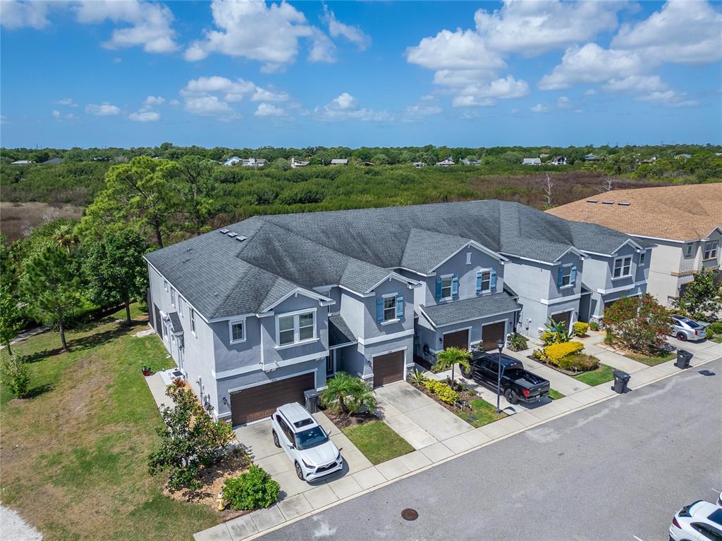 An aerial view shows a multi-unit residential building with gray siding, dark roofs, and driveways — 8108 MUDDY PINES PLACE UNIT 8108, TAMPA, FL