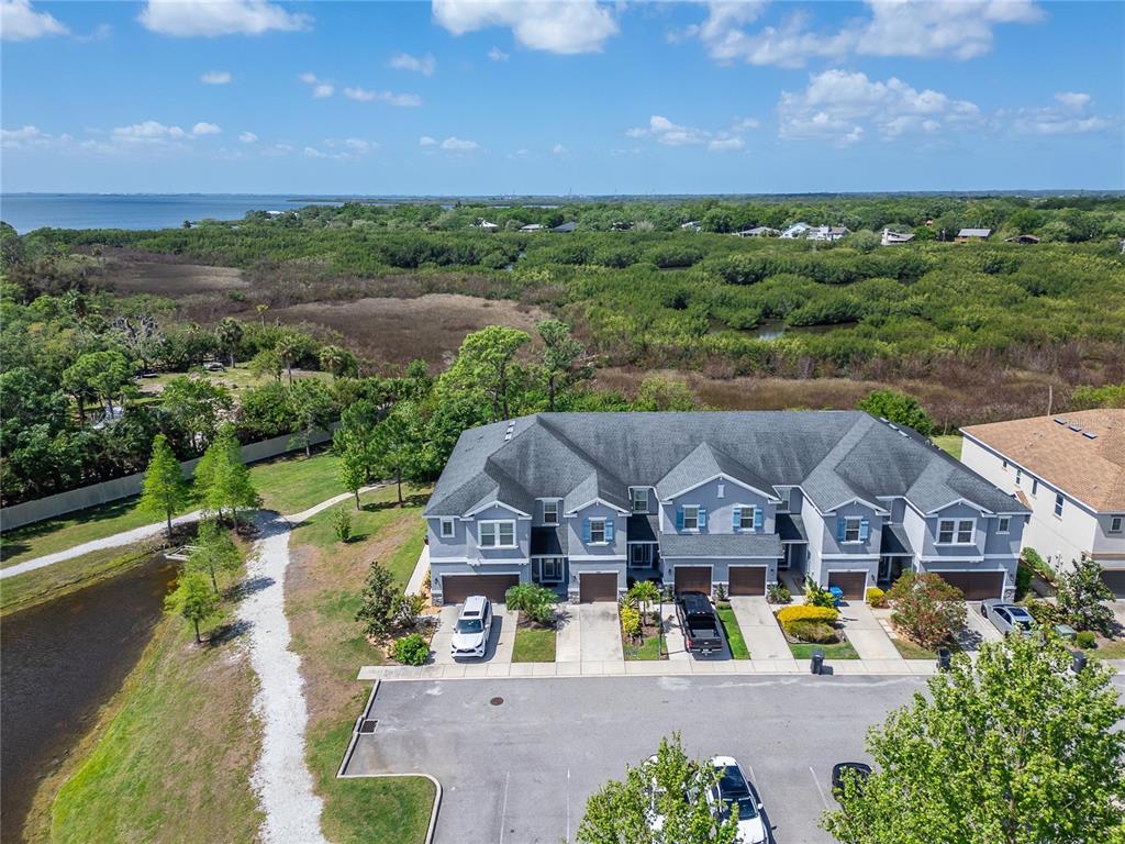 An aerial view shows a multi-unit townhouse building with attached garages and a nearby pond — 8108 MUDDY PINES PLACE UNIT 8108, TAMPA, FL