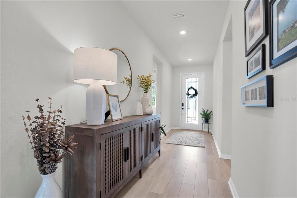 A bright entryway features light wood flooring, a wooden console table, and a glass-paneled door — 37557 MACKENZIE DRIVE, ZEPHYRHILLS, FL