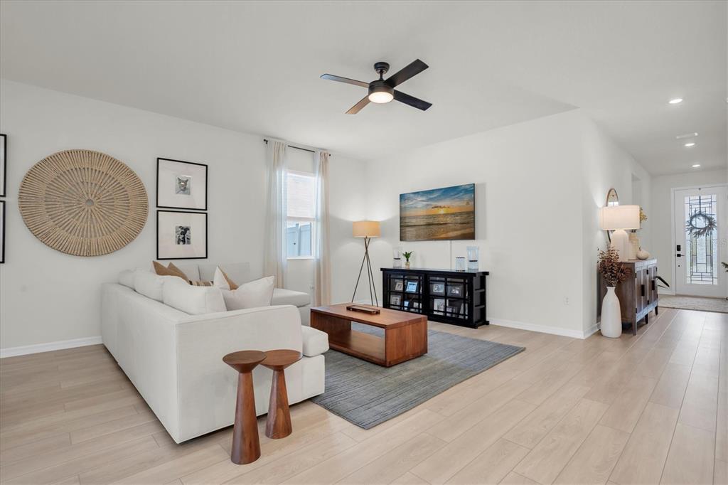 A bright living room features a white sofa, wooden coffee table, and a ceiling fan — 37557 MACKENZIE DRIVE, ZEPHYRHILLS, FL