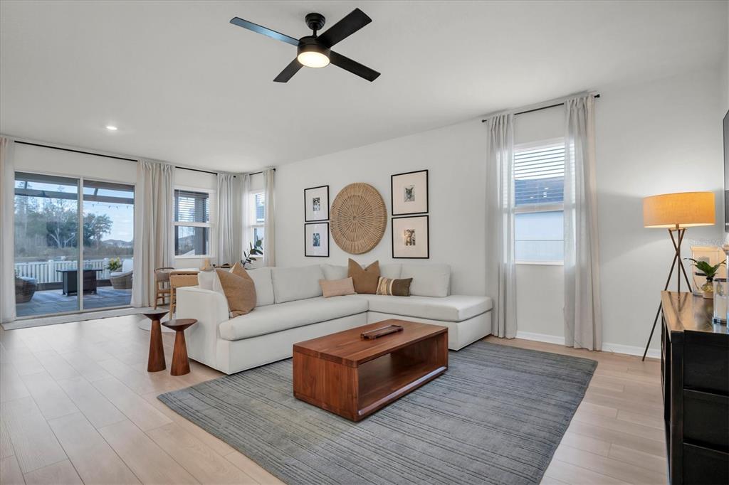 A bright living room features a white sectional sofa, wood coffee table, and ceiling fan — 37557 MACKENZIE DRIVE, ZEPHYRHILLS, FL