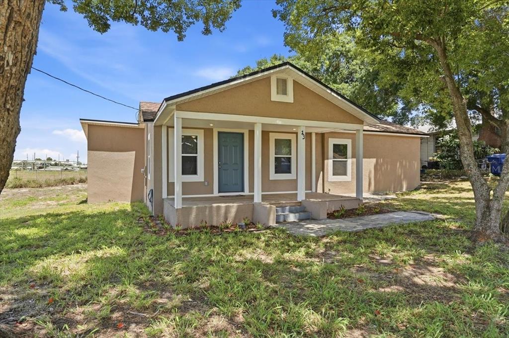 A tan, single-story house with a covered front porch and a blue front door — 13 E 8TH STREET, FROSTPROOF, FL