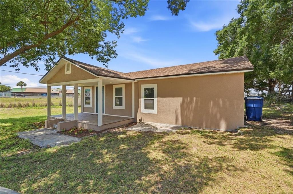 A tan, single-story house with a covered front porch and a brown shingled roof — 13 E 8TH STREET, FROSTPROOF, FL