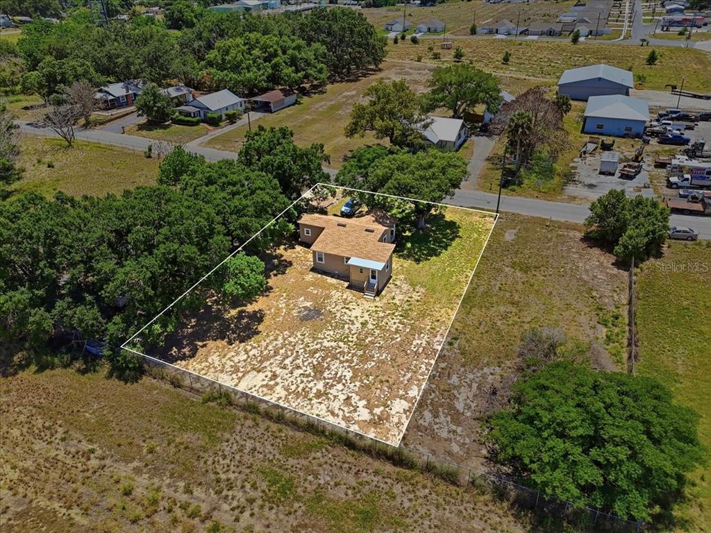 An aerial view shows a single-story house with a tan roof on a fenced lot — 13 E 8TH STREET, FROSTPROOF, FL