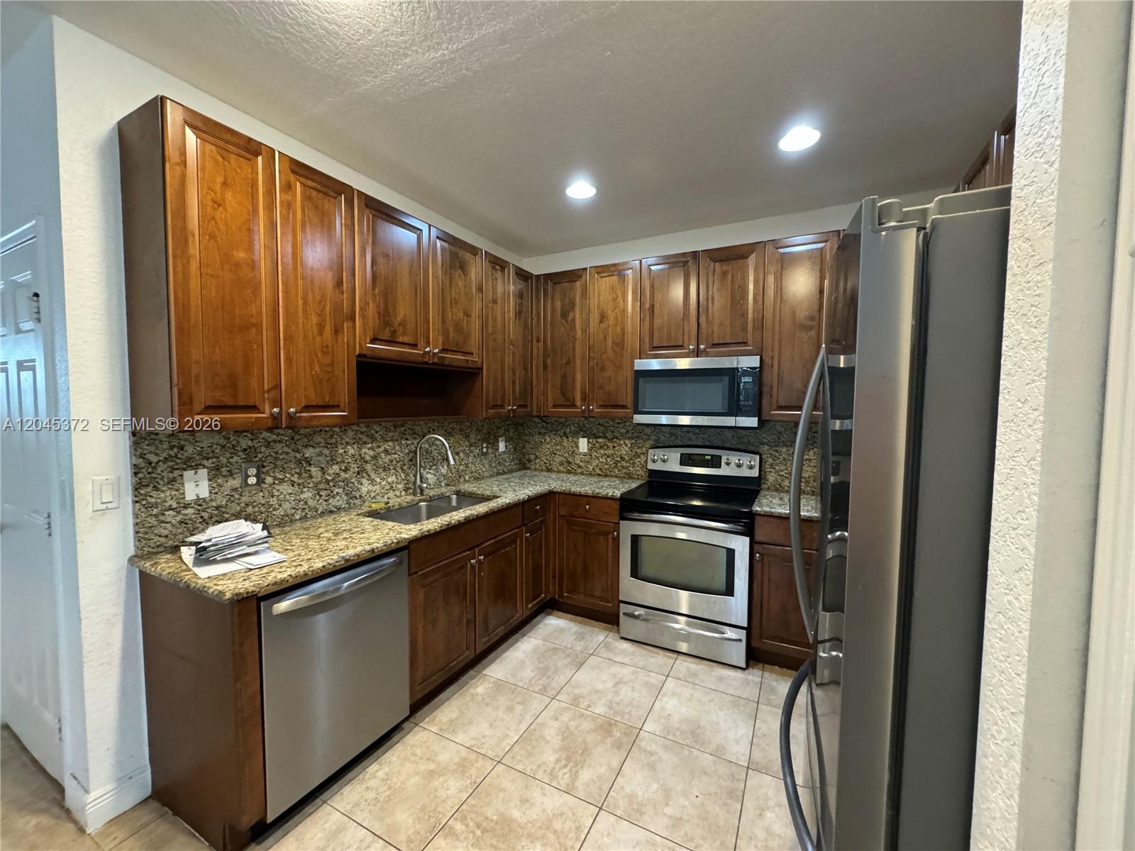 A kitchen features dark wood cabinets, granite countertops, and stainless steel appliances — 9763 Darlington Pl # 9763, Cooper City FL 33328, COOPER CITY, FL