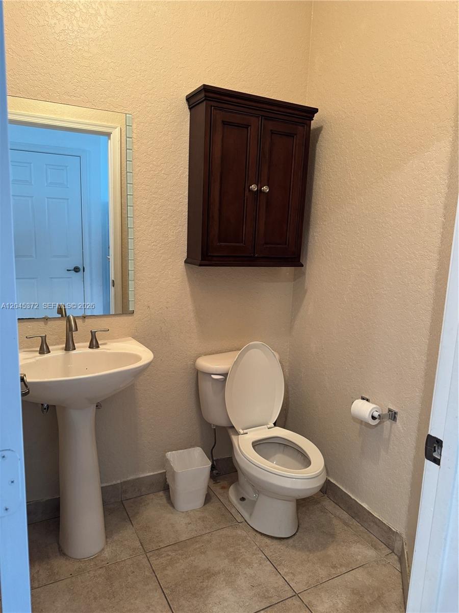 A small bathroom features a pedestal sink, a toilet, and a dark wood wall cabinet — 9763 Darlington Pl # 9763, Cooper City FL 33328, COOPER CITY, FL
