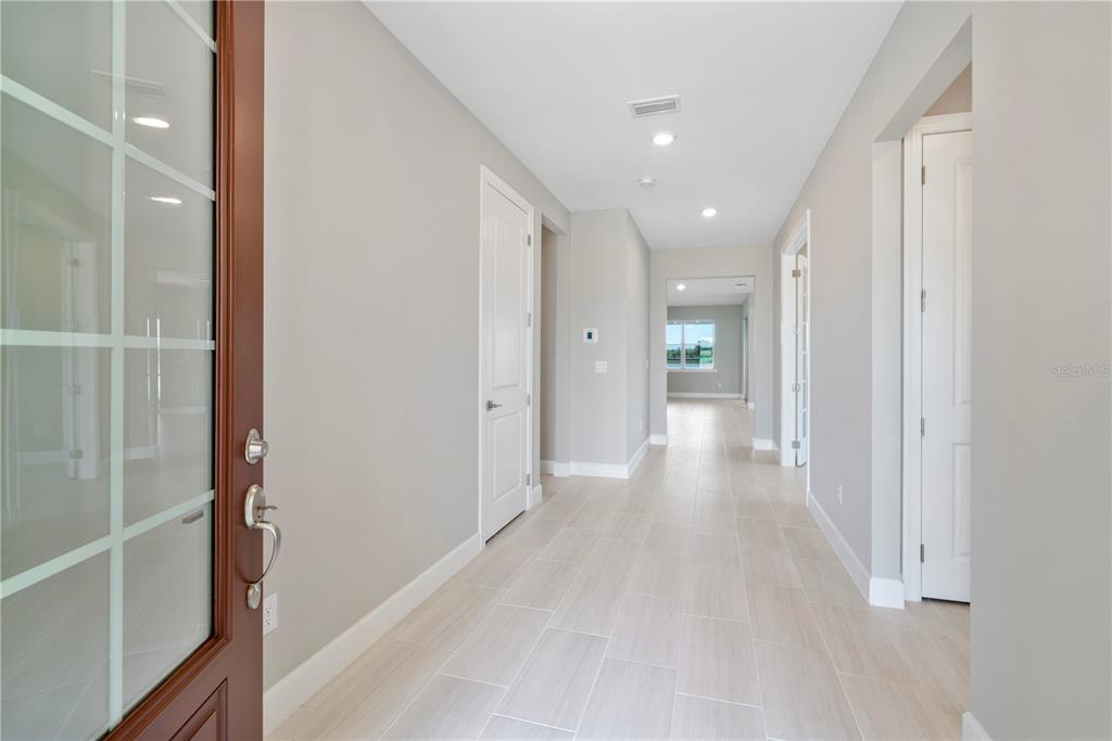A bright entryway features light-colored tile flooring, white doors, and a view toward a window — 16056 SHORELINE DRIVE, PUNTA GORDA, FL