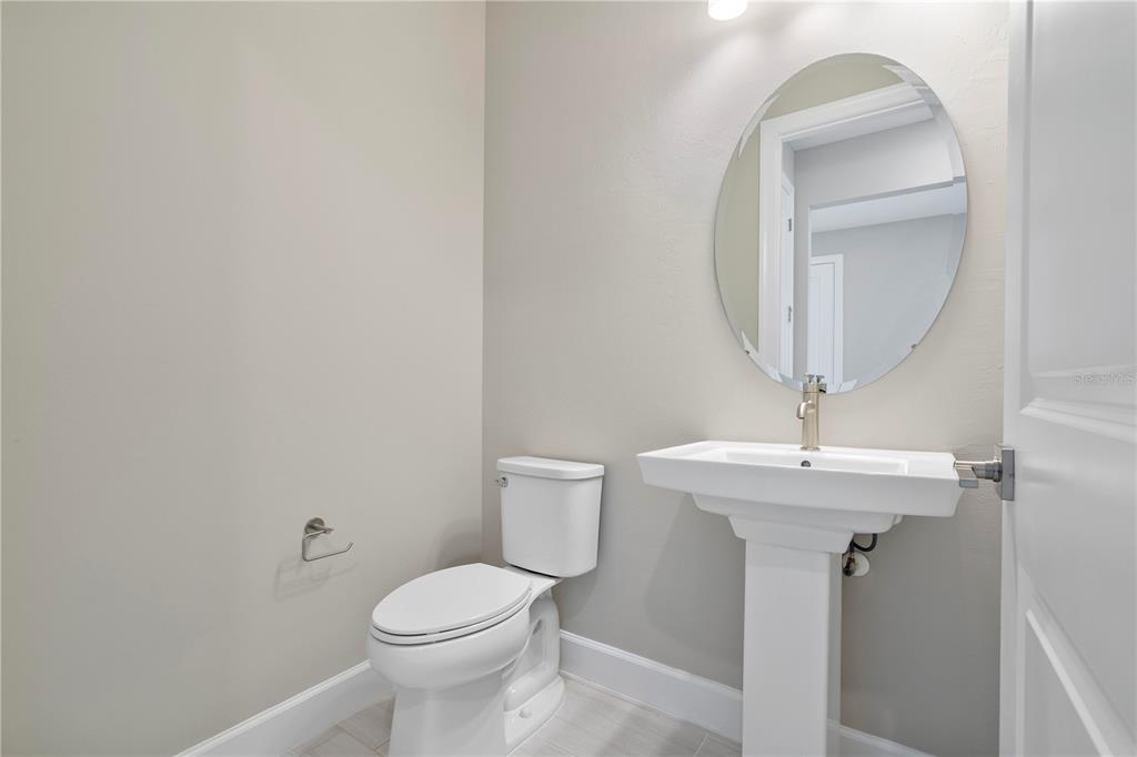 A half bathroom features a pedestal sink, an oval mirror, and a white toilet — 16056 SHORELINE DRIVE, PUNTA GORDA, FL