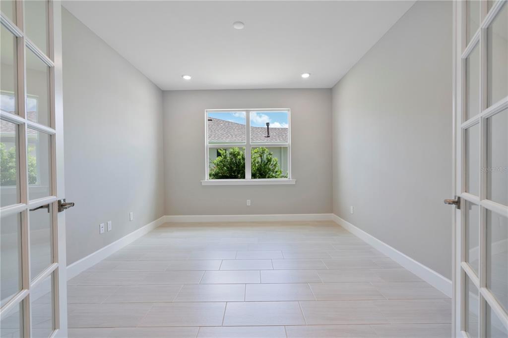 A bright room with light gray walls, white tile flooring, and French doors — 16056 SHORELINE DRIVE, PUNTA GORDA, FL