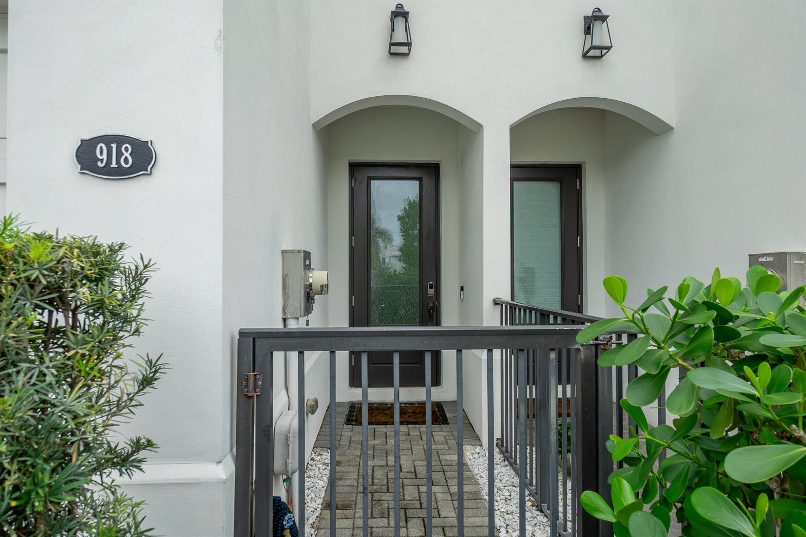 A gated entryway with a paved walkway leads to a dark-framed glass front door — 918 St George Boulevard, Delray Beach FL 33483, DELRAY BEACH, FL