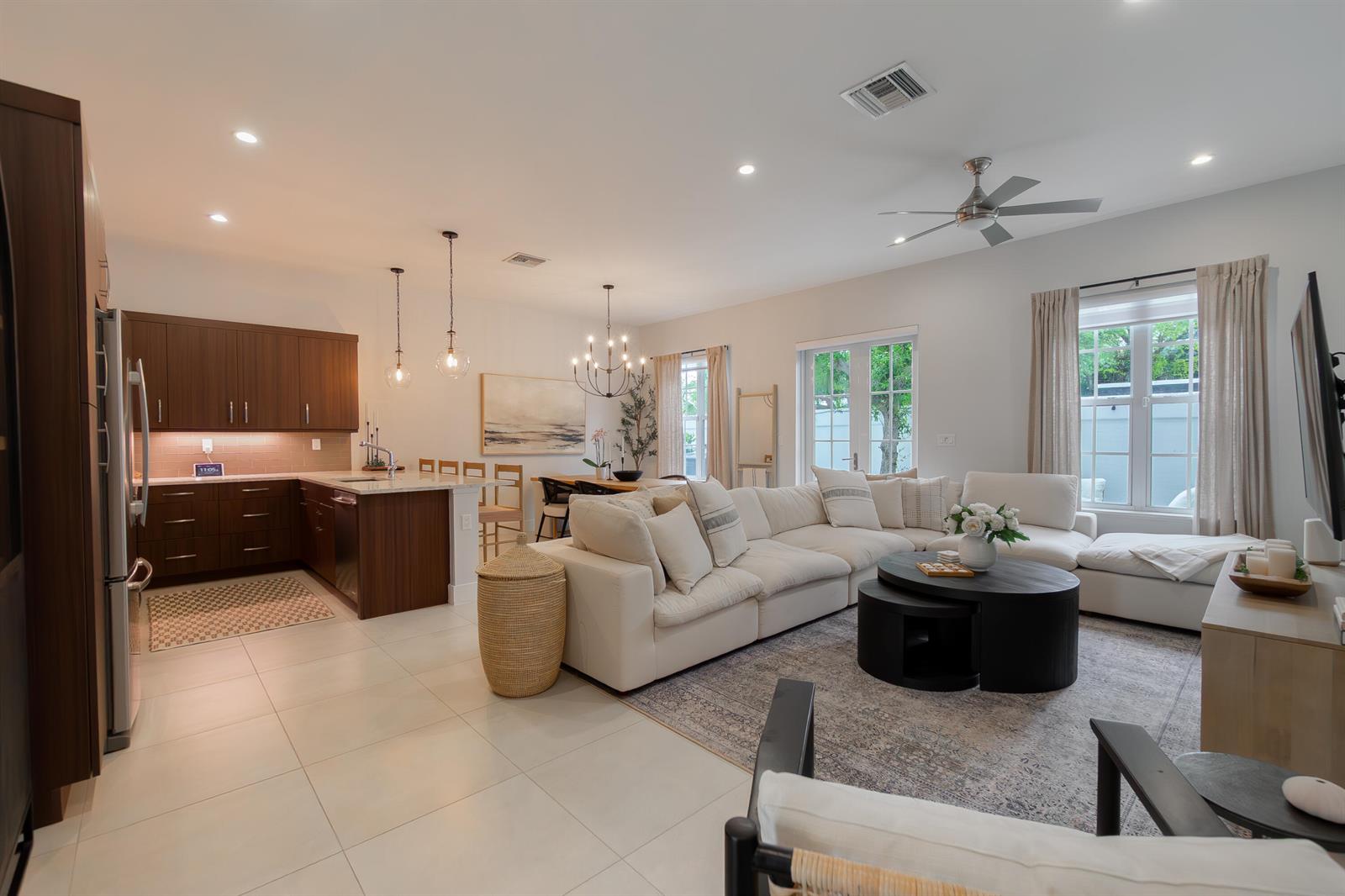 An open-concept living room and kitchen featuring a white sectional sofa and dark wood cabinetry — 918 St George Boulevard, Delray Beach FL 33483, DELRAY BEACH, FL