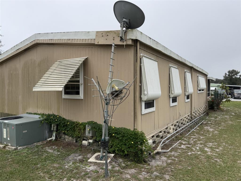The exterior of a tan mobile home features a satellite dish and a television antenna — 9072 LAKE POINT BOULEVARD, LAKE WALES, FL