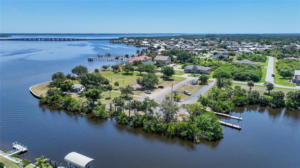 An aerial view shows a waterfront neighborhood with houses, docks, and a park area — 12121 SNOW BIRD AVENUE, PORT CHARLOTTE, FL
