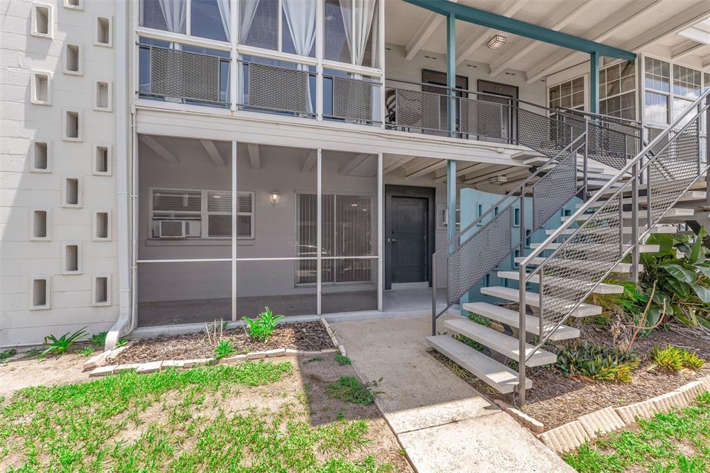 An exterior view of a two-story apartment building with a screened-in patio and metal staircase — 151 NORTH ORLANDO AVENUE UNIT 142, WINTER PARK, FL