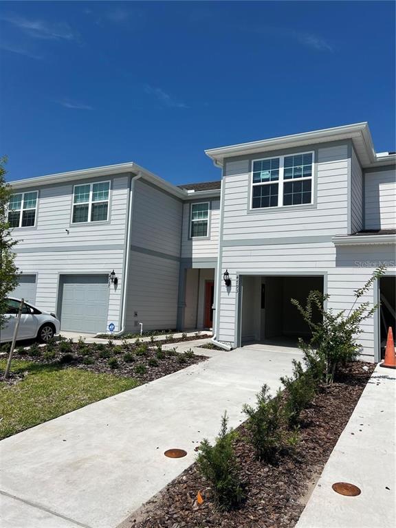 The exterior of a two-story townhouse features light gray siding, a garage, and a concrete driveway — 4793 SPARKLING SHELL AVENUE, KISSIMMEE, FL