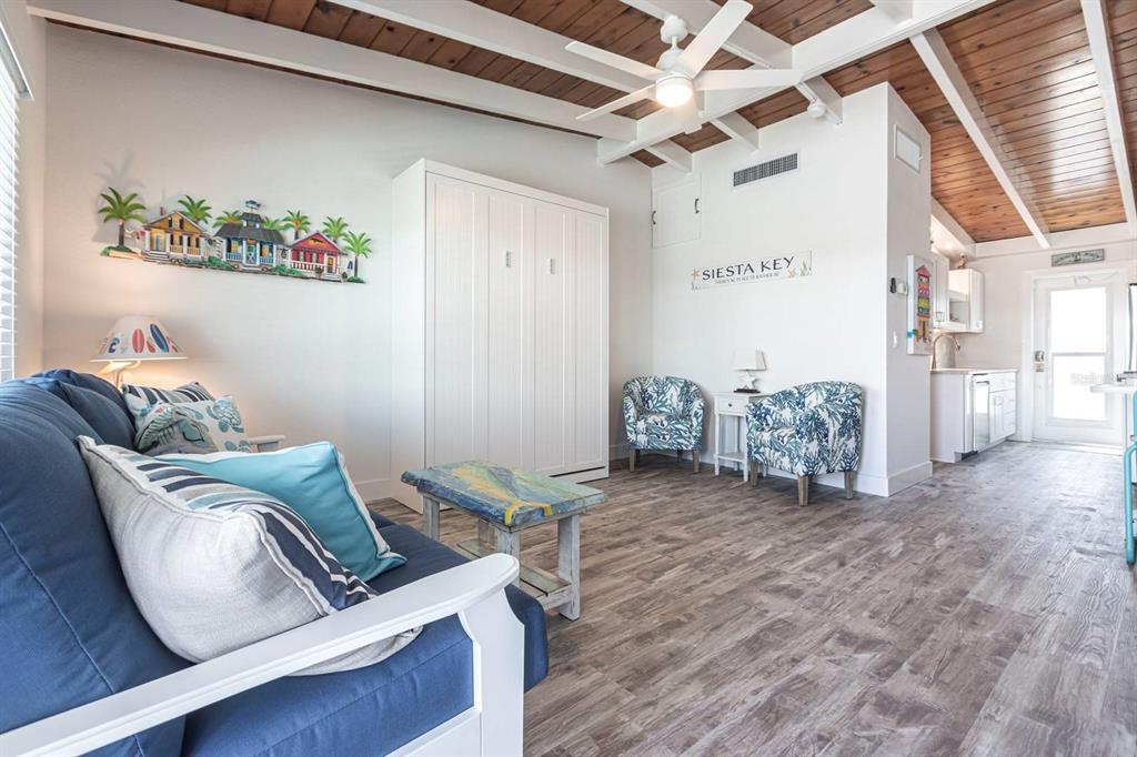 A living room features a blue sofa, a Murphy bed, and wood-paneled vaulted ceilings — 6006 MIDNIGHT PASS ROAD UNIT 29, SARASOTA, FL