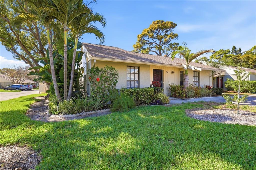 A single-story house with a tan exterior, palm trees, and a green lawn — 36 WINDRUSH BAY DRIVE UNIT 36, TARPON SPRINGS, FL