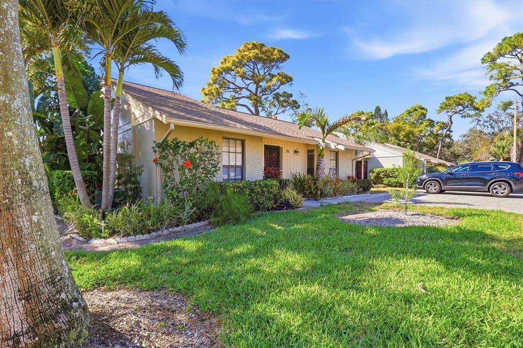 A single-story house with a tan exterior, palm trees, and a car parked in front — 36 WINDRUSH BAY DRIVE UNIT 36, TARPON SPRINGS, FL