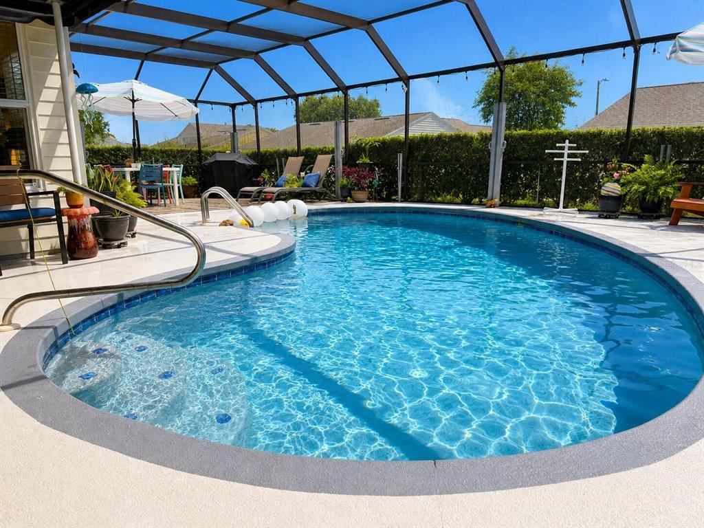 A screened-in swimming pool with a patio, lounge chairs, and dining area — 1018 PARAKEET TRAIL, LAKELAND, FL