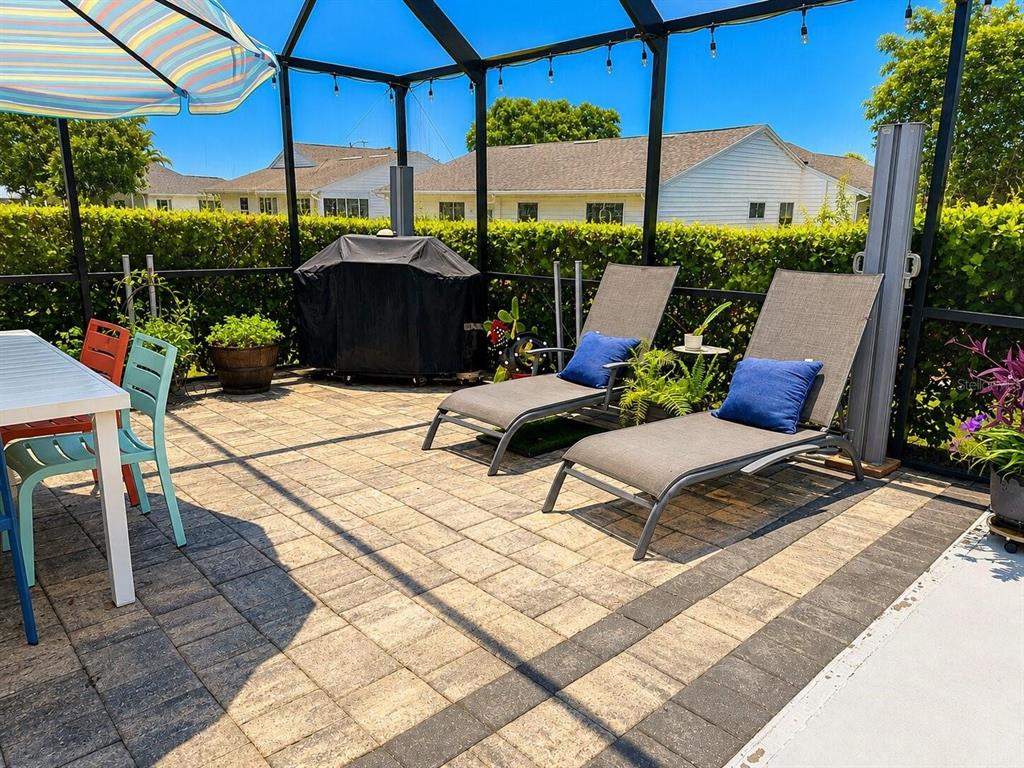 A screened-in patio features a dining set, two lounge chairs, and a covered grill — 1018 PARAKEET TRAIL, LAKELAND, FL