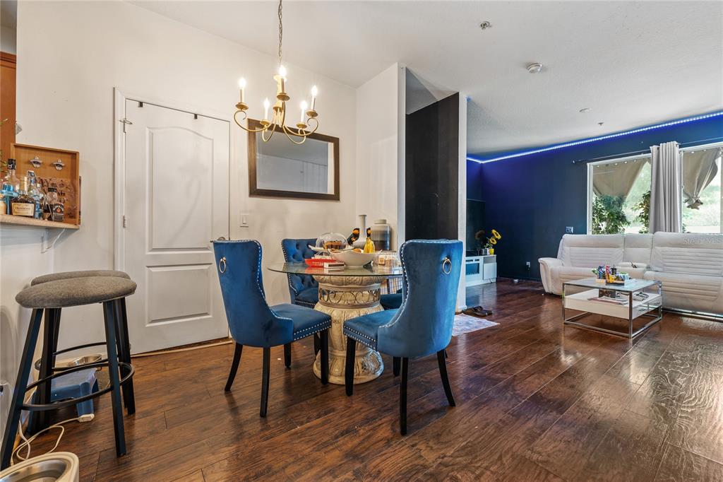 A dining area with a glass table and blue chairs sits adjacent to a living room — 6039 STRADA ISLE WAY, ORLANDO, FL