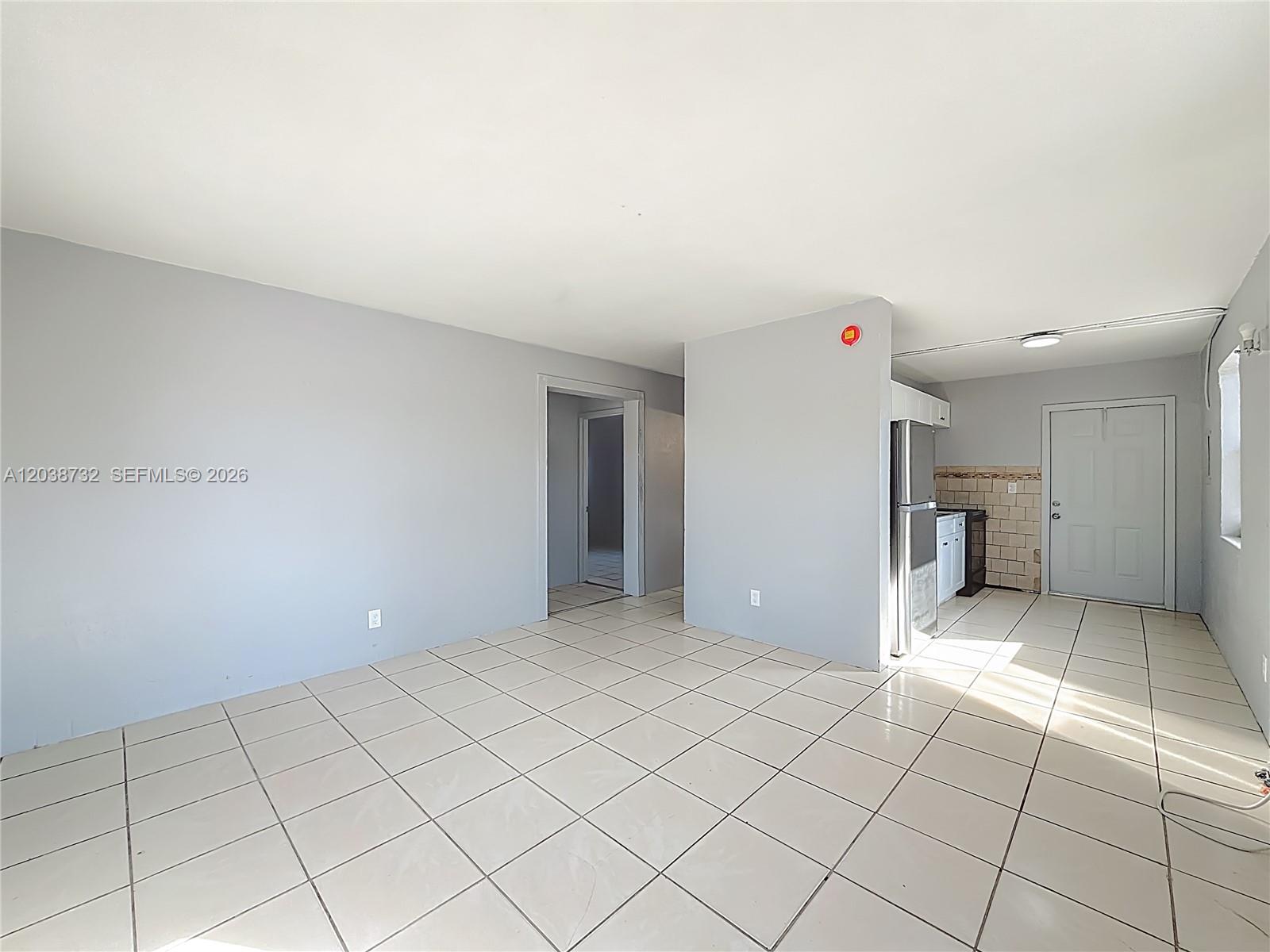 An open-concept living area features light gray walls, white tile flooring, and an adjacent kitchen — 2408 NW 8th St # 0, Pompano Beach FL 33069, POMPANO BEACH, FL