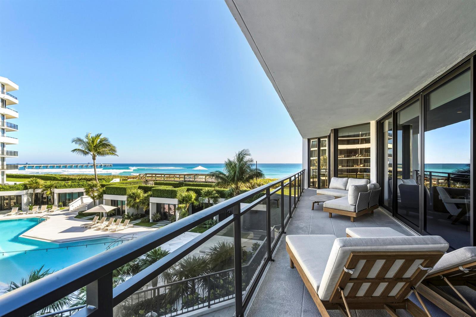 A balcony with lounge furniture overlooks a swimming pool, landscaped grounds, and the ocean — 3100 S Ocean Boulevard # 201s, Palm Beach FL 33480, PALM BEACH, FL