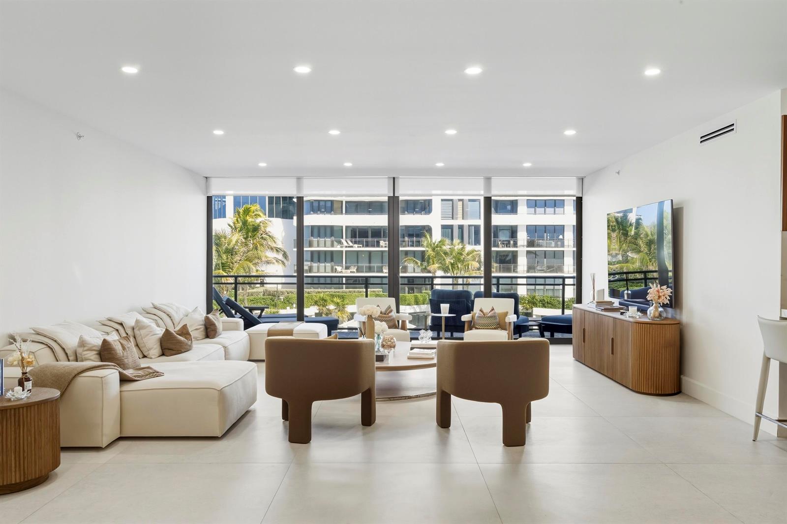 A modern living room with a white sectional, two tan armchairs, and floor-to-ceiling windows — 3100 S Ocean Boulevard # 201s, Palm Beach FL 33480, PALM BEACH, FL