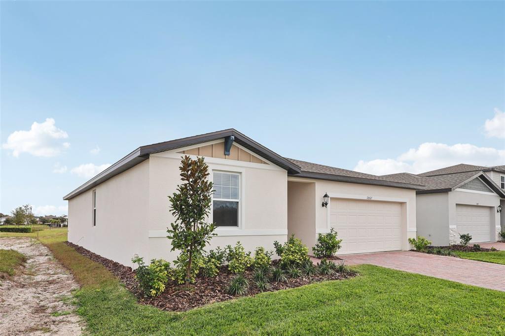 A single-story house with a beige stucco exterior, a two-car garage, and a landscaped yard — 2867 HORNBILL DRIVE, ST CLOUD, FL