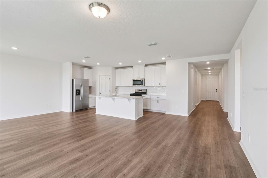 An open-concept kitchen with white cabinets, stainless steel appliances, and wood-look flooring — 2867 HORNBILL DRIVE, ST CLOUD, FL