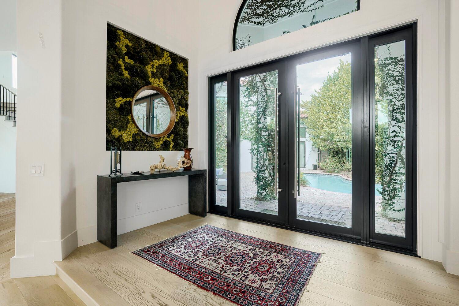 An entryway features a moss wall, a dark console table, and glass doors overlooking a pool — 6179 Vía Venetia S, Delray Beach FL 33484, DELRAY BEACH, FL
