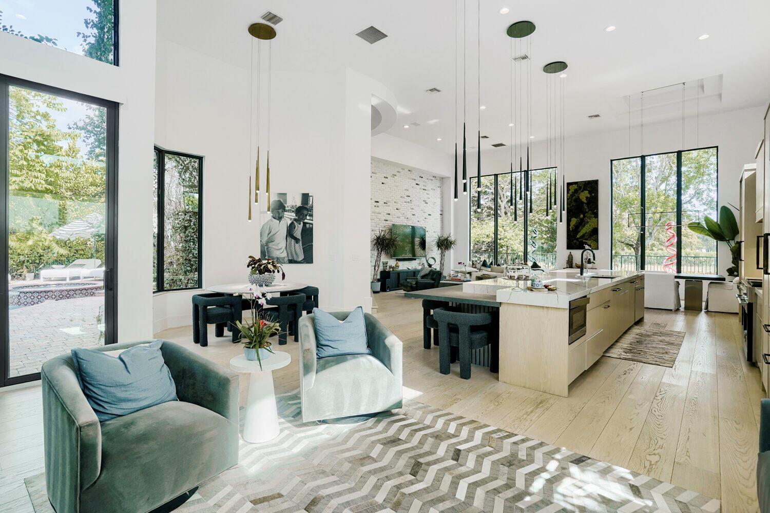 A modern open-concept kitchen and living area with light wood floors and floor-to-ceiling windows — 6179 Vía Venetia S, Delray Beach FL 33484, DELRAY BEACH, FL