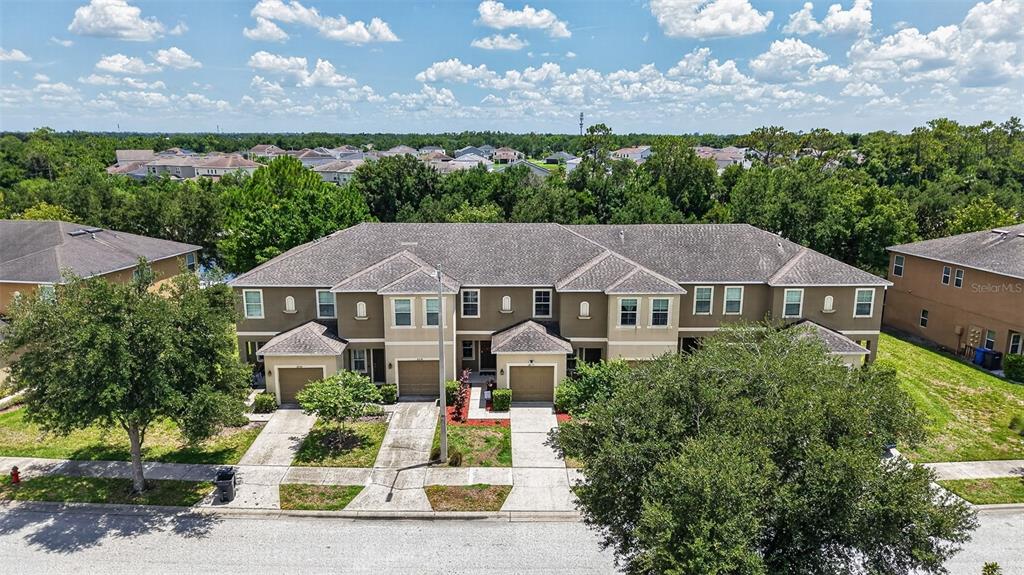 An aerial view shows a multi-unit townhouse building with brown siding and attached garages — 6710 HOLLY HEATH DRIVE, RIVERVIEW, FL
