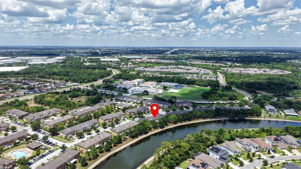 An aerial view shows a residential neighborhood with townhomes situated along a winding canal — 6710 HOLLY HEATH DRIVE, RIVERVIEW, FL