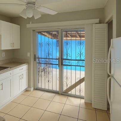 A kitchen with white cabinets, tile floors, and a sliding glass door with security bars — 3011 ERNEST DRIVE, AUBURNDALE, FL