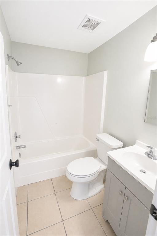 A bathroom features a white tub-shower combo, a toilet, and a gray vanity with a sink — 3011 ERNEST DRIVE, AUBURNDALE, FL