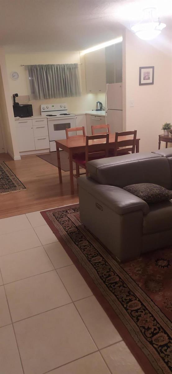 A kitchen with white cabinets and a dining table sits adjacent to a living area — 2687 Garden Drive N # 108, FL 33461, FL