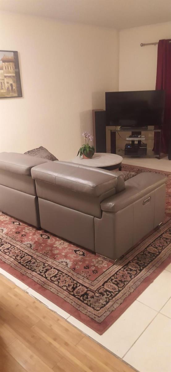 A living room features a gray leather sectional sofa on a patterned rug — 2687 Garden Drive N # 108, FL 33461, FL