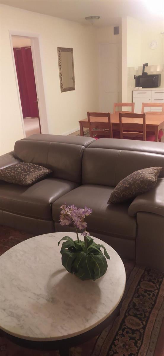 A living room with a grey leather sofa, marble coffee table, and adjacent dining area — 2687 Garden Drive N # 108, FL 33461, FL