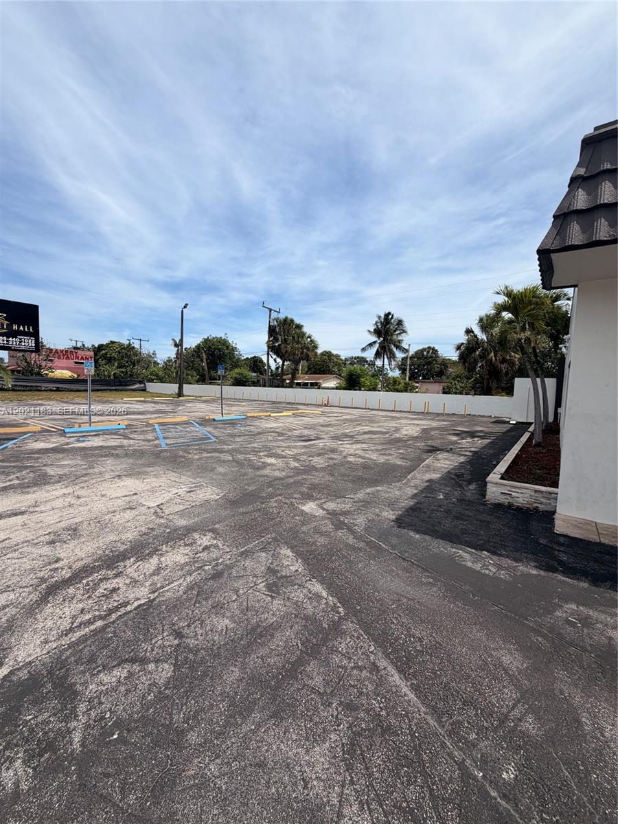 An outdoor parking lot with marked spaces sits beside a building with a shingled roof — 920 NW 119th St, Miami FL 33168, MIAMI, FL