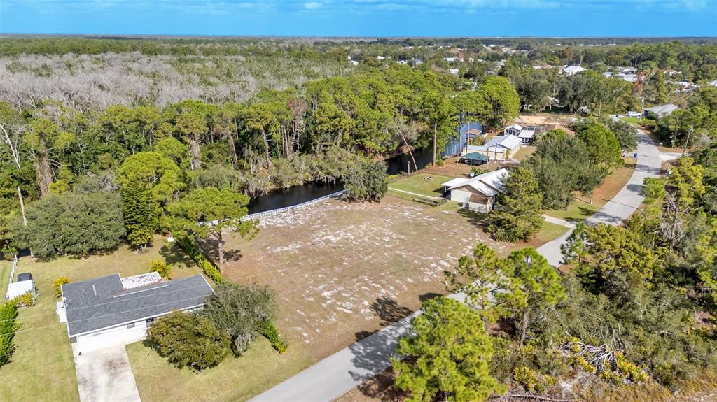 An aerial view shows a vacant, sandy lot situated between two houses and a canal — 1102 SYCAMORE STREET, LAKE PLACID, FL