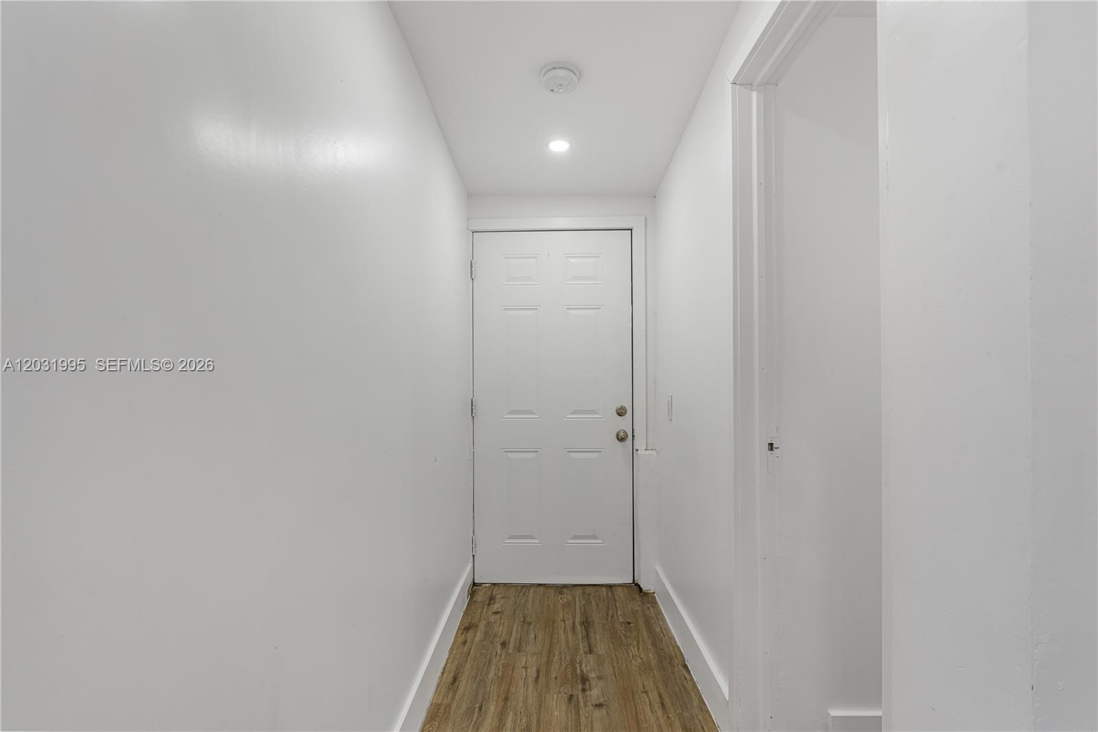 A narrow hallway features white walls, a single door, and wood-look flooring — 2290 Rutland St, Opa-Locka FL 33054, OPA-LOCKA, FL