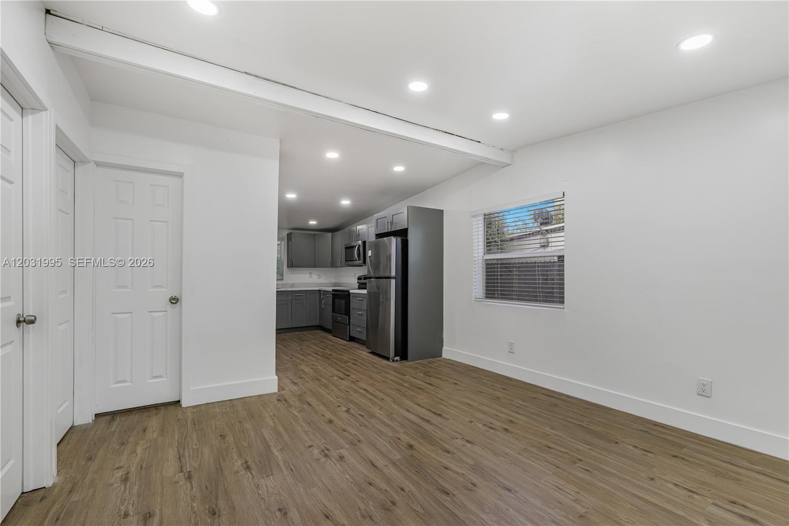 This room features light wood-look flooring, white walls, recessed lighting, and an adjacent kitchen — 2290 Rutland St, Opa-Locka FL 33054, OPA-LOCKA, FL