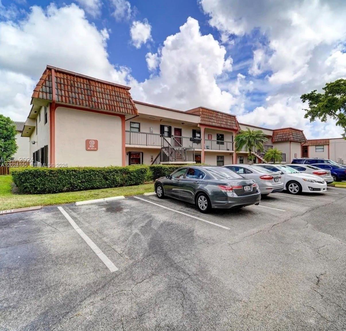 A two-story apartment building with a tiled roof and a parking lot in front — 851 NE 207th Ter # 103, Miami FL 33179, MIAMI, FL