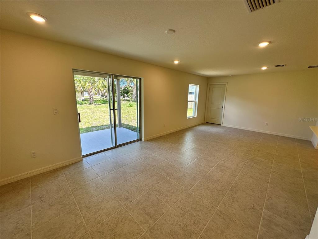 A bright, tiled living area features sliding glass doors opening to a grassy backyard — 41 ROUND TREE DRIVE, PALM COAST, FL