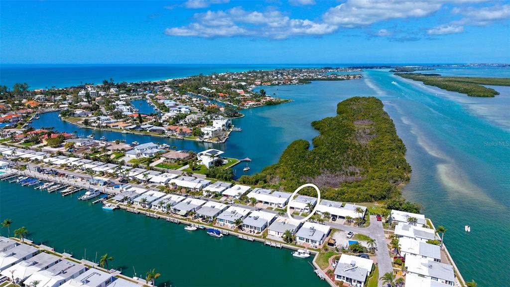 An aerial view shows a waterfront residential community with a circled unit and boat docks — 909 SPANISH DRIVE N, LONGBOAT KEY, FL