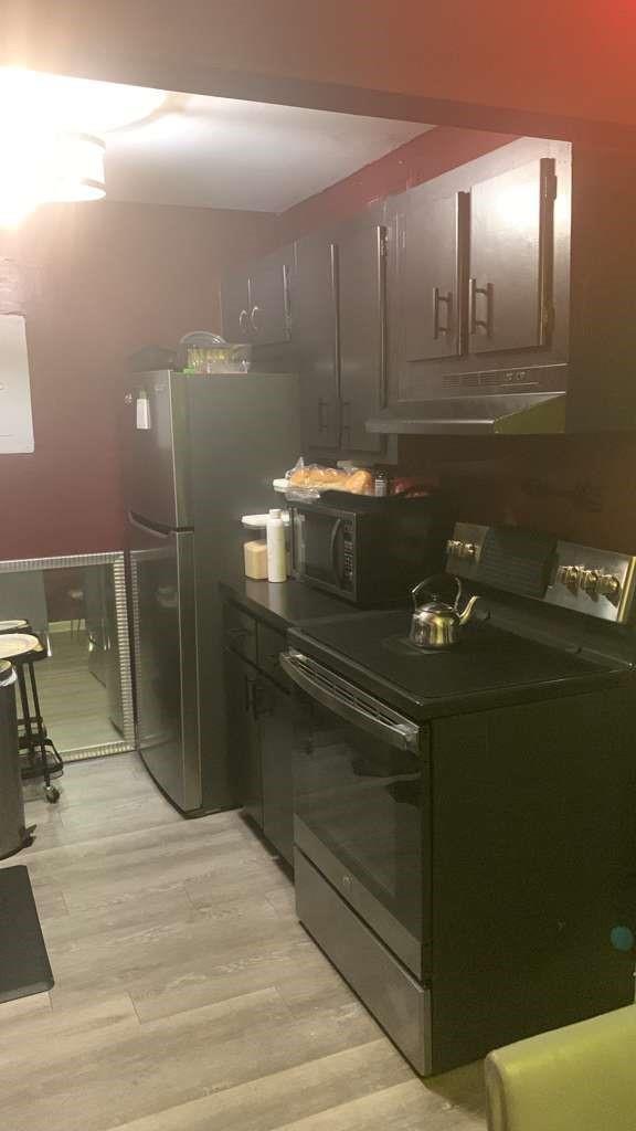 A kitchen features dark cabinets, stainless steel appliances, and light-colored wood-look flooring — 1333 S Dixie Highway # 202, Deerfield Beach FL 33441, DEERFIELD BEACH, FL